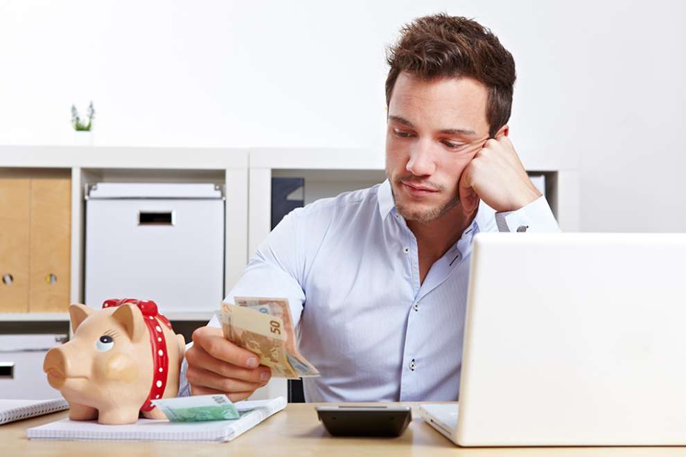 Foto: Mann mit Taschenrechner und Bargeld