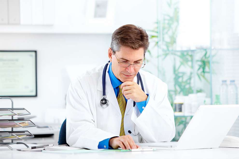 Foto: Arzt sitzt vor Laptop